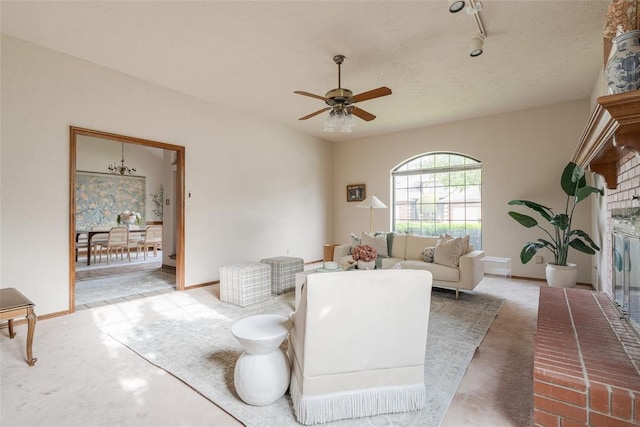carpeted living area with ceiling fan with notable chandelier, baseboards, and rail lighting