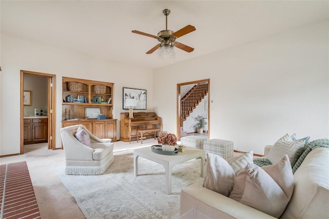 living area with baseboards, a ceiling fan, and light carpet