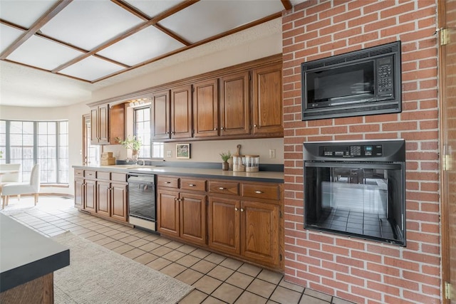 kitchen featuring brown cabinetry, light tile patterned flooring, a glass covered fireplace, and black appliances