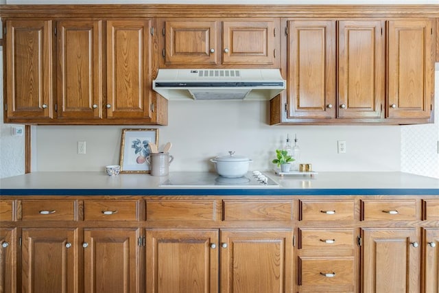 kitchen with under cabinet range hood, light countertops, brown cabinetry, and black electric cooktop