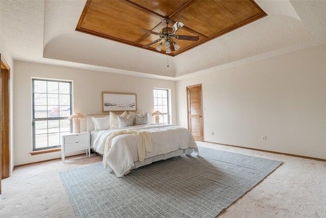 bedroom featuring light carpet, multiple windows, and a tray ceiling