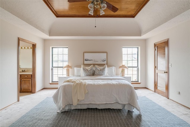 bedroom featuring multiple windows, a tray ceiling, and baseboards