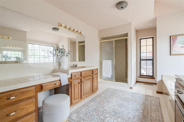 full bathroom with a bath, a textured ceiling, vanity, tile patterned flooring, and a stall shower