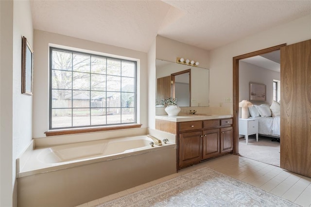full bath featuring a textured ceiling, a garden tub, vanity, and ensuite bath