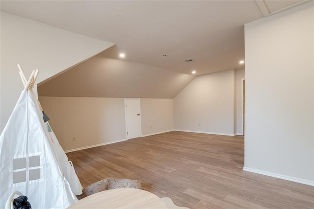 additional living space with baseboards, light wood finished floors, recessed lighting, and lofted ceiling