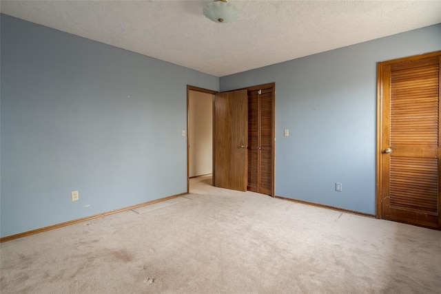 unfurnished bedroom with carpet floors, baseboards, and a textured ceiling