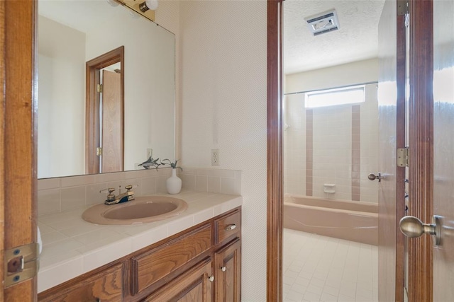 full bath featuring a textured ceiling, vanity, tile patterned flooring, and tub / shower combination