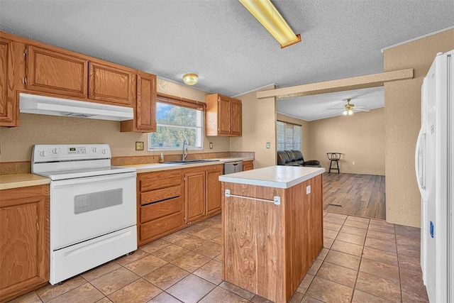 kitchen with under cabinet range hood, white appliances, a sink, light countertops, and a center island