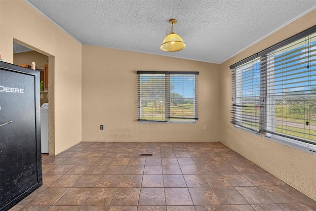 tiled empty room featuring lofted ceiling, visible vents, a textured wall, a textured ceiling, and washer / dryer