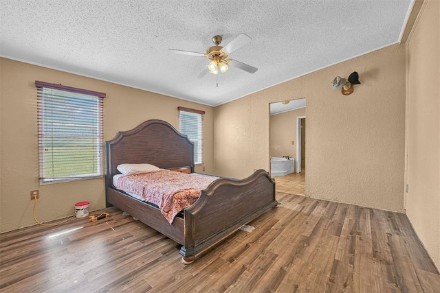 bedroom featuring lofted ceiling, a textured wall, a textured ceiling, and wood finished floors