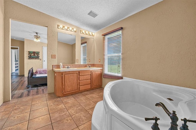 full bath featuring a textured ceiling, a textured wall, ensuite bath, and a sink