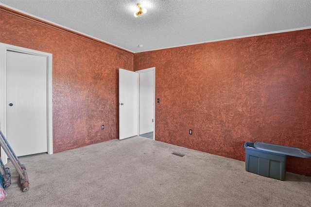 carpeted spare room featuring a textured ceiling and crown molding