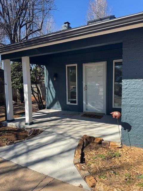 property entrance with fence and brick siding