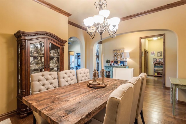 dining room featuring arched walkways, dark wood finished floors, an inviting chandelier, ornamental molding, and baseboards