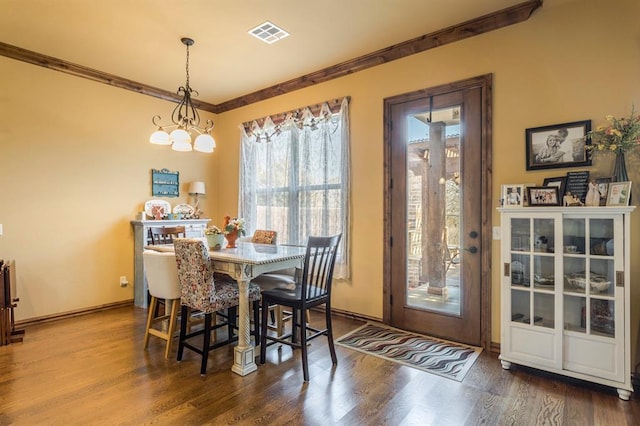 dining room with dark wood-style floors, a notable chandelier, visible vents, and crown molding