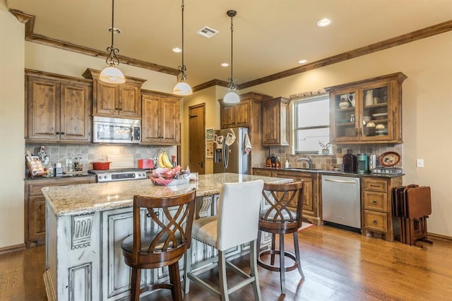 kitchen with dark wood-style flooring, appliances with stainless steel finishes, brown cabinetry, and a sink