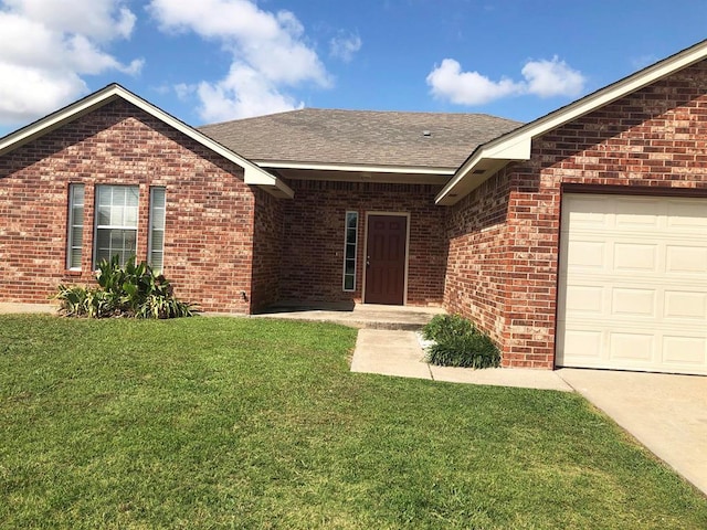 view of front of house with an attached garage, brick siding, a shingled roof, and a front yard