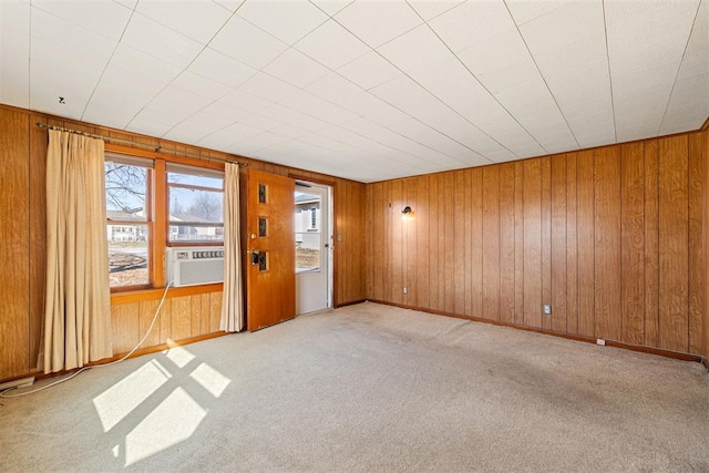 carpeted spare room featuring wooden walls, cooling unit, and baseboards