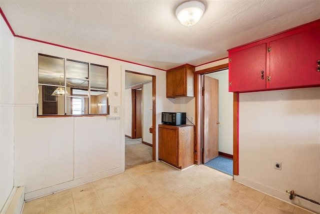 kitchen with light floors, baseboards, and black microwave