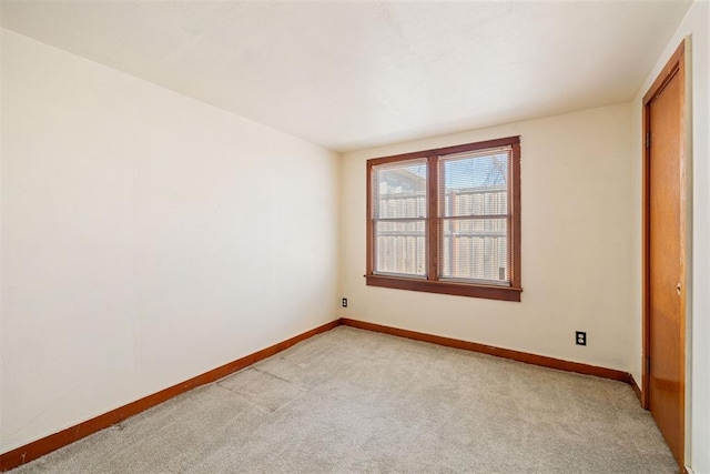 unfurnished room with baseboards and light carpet