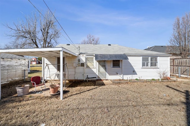 rear view of house with fence and a shingled roof