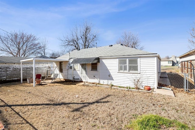 back of property with roof with shingles and fence