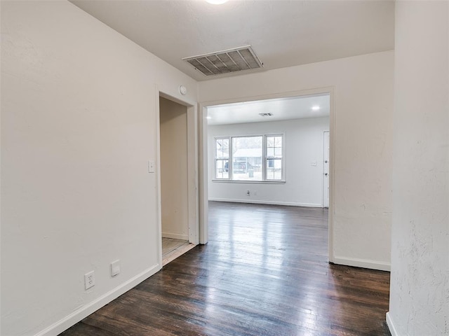 spare room featuring dark wood-type flooring, visible vents, and baseboards