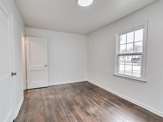 unfurnished room featuring dark wood-type flooring and baseboards