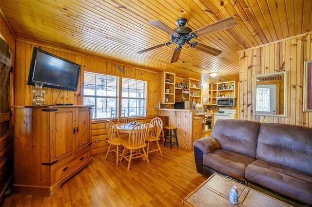 living room featuring wooden ceiling, light wood-style flooring, wooden walls, and a ceiling fan