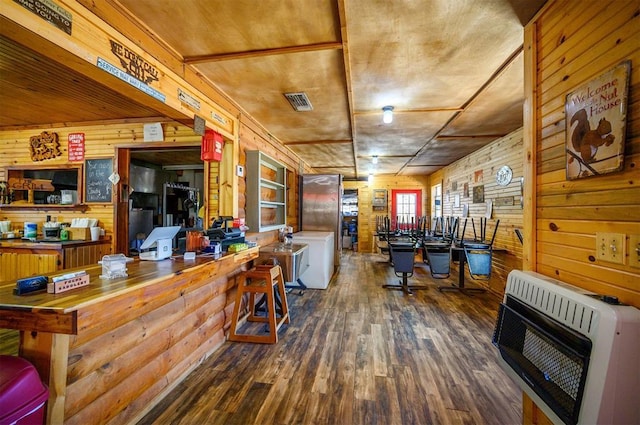 interior space featuring heating unit, wood walls, visible vents, and wood finished floors