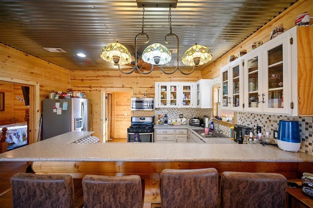 kitchen featuring wooden walls, appliances with stainless steel finishes, backsplash, and a sink