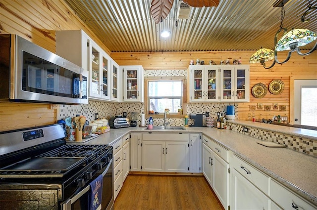 kitchen featuring stainless steel appliances, a sink, white cabinetry, light wood-type flooring, and tasteful backsplash