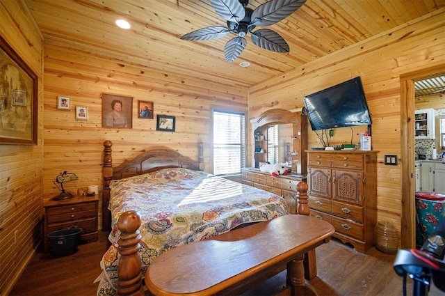 bedroom featuring wooden ceiling, wood finished floors, a ceiling fan, and wooden walls