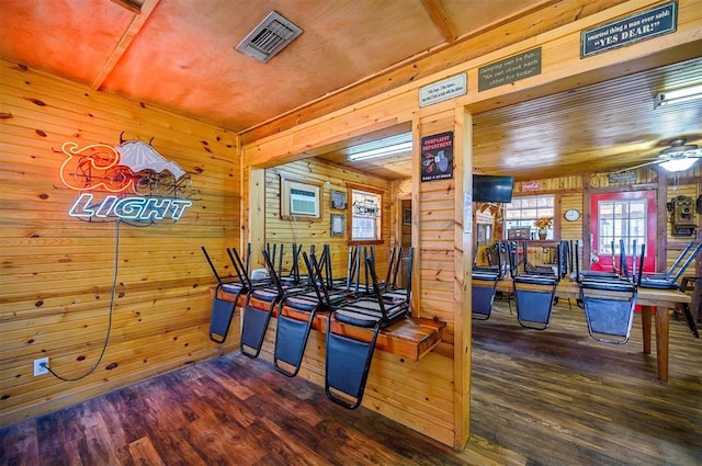 dining area with a ceiling fan, wood walls, visible vents, wooden ceiling, and wood finished floors