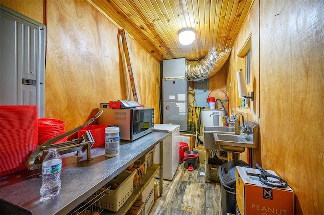 kitchen with stainless steel microwave, a sink, heating unit, wooden ceiling, and wood finished floors