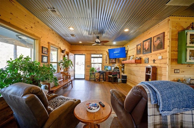 living room featuring ceiling fan, visible vents, recessed lighting, wood finished floors, and wood walls