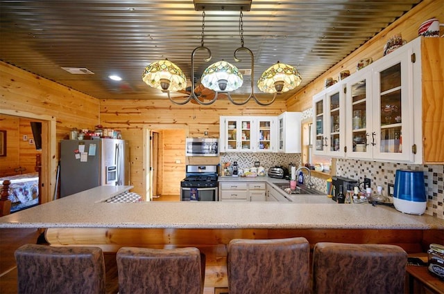 kitchen featuring wood walls, a sink, backsplash, and appliances with stainless steel finishes