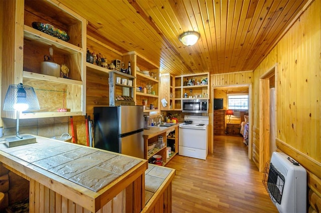 kitchen featuring heating unit, open shelves, appliances with stainless steel finishes, tile countertops, and a sink