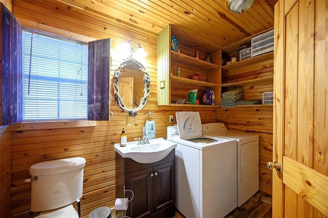 clothes washing area featuring a sink, wood walls, washing machine and clothes dryer, and wooden ceiling