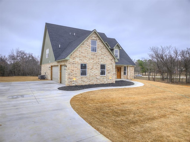 view of front of home featuring driveway, a garage, a front lawn, central AC, and brick siding