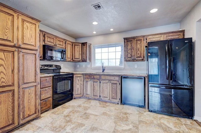 kitchen with visible vents, light countertops, brown cabinetry, black appliances, and a sink