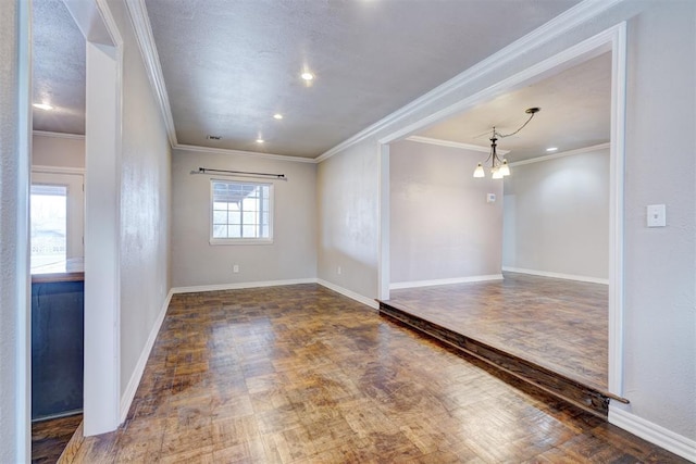 empty room featuring baseboards, an inviting chandelier, wood finished floors, and crown molding