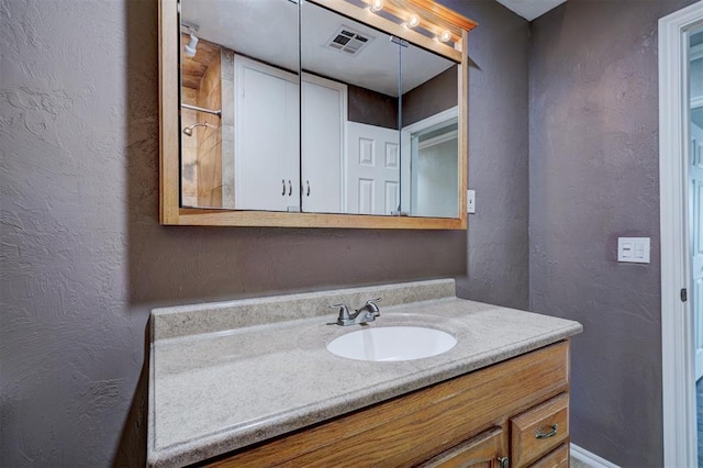 bathroom with vanity, a textured wall, and visible vents