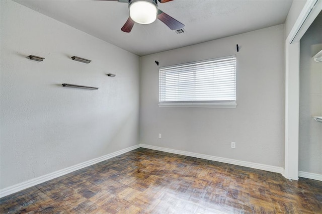 spare room featuring visible vents, wood finished floors, baseboards, and ceiling fan