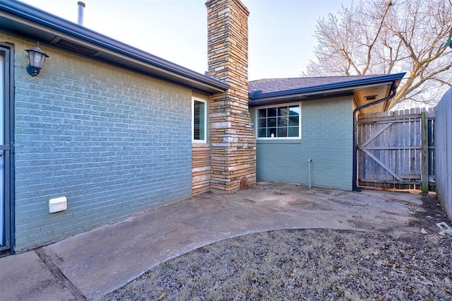 exterior space with a patio, brick siding, a chimney, and fence