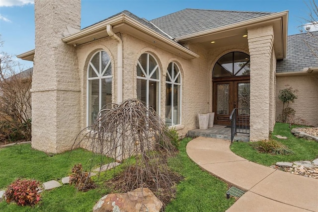 property entrance featuring french doors, a chimney, a shingled roof, and stucco siding