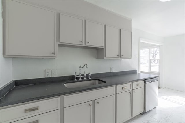 kitchen with dishwasher, dark countertops, marble finish floor, white cabinetry, and a sink