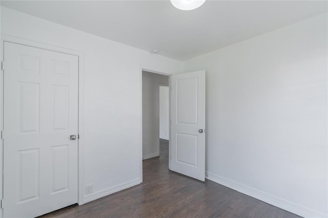 unfurnished bedroom with dark wood-type flooring and baseboards