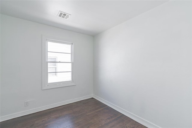 unfurnished room with baseboards, visible vents, and dark wood-style flooring