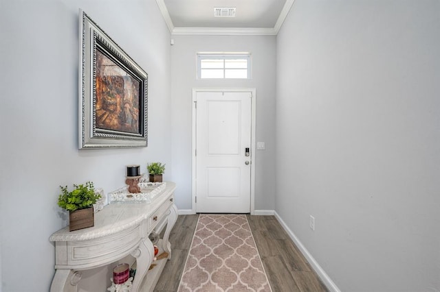 doorway featuring visible vents, ornamental molding, baseboards, and wood finished floors